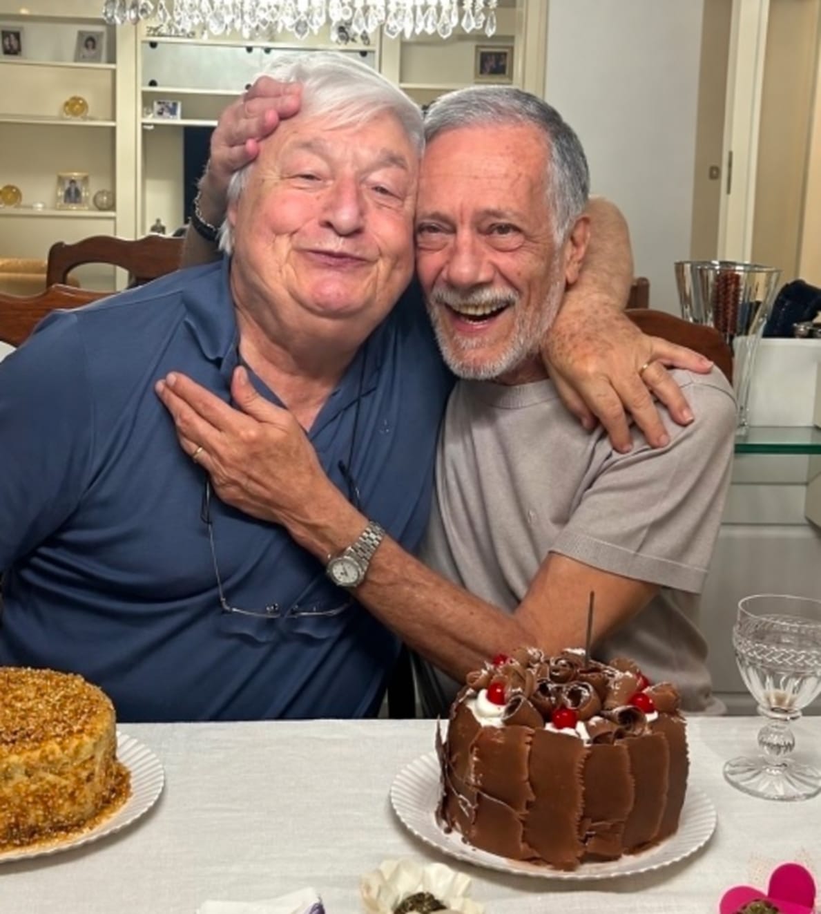 Roberto Maffeis à esquerda e Paolo Camozzi à direita, abraçados e sorrindo diante de bolos.